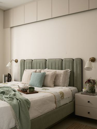 Sage green fluted headboard bed with brass sconces and a styled breakfast tray in a neutral bedroom