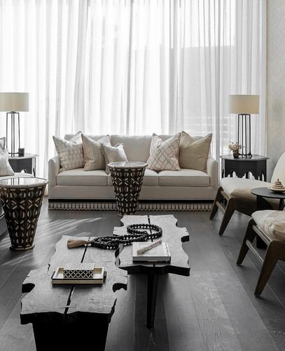 Symmetrical living room with cream sofa, dark live-edge tables, and inlaid moroccan side tables against sheer curtains