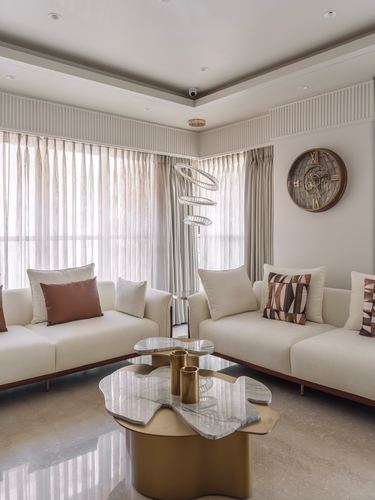 Ivory living room with two sofas, sculptural marble coffee table, and gold wall clock