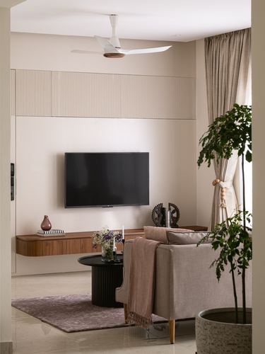 Neutral living room with floating wood console, fluted wall panel, TV, and beige sofa