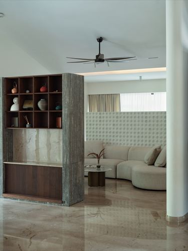 Living room with curved beige sofa, stone display partition, and patterned wall behind window