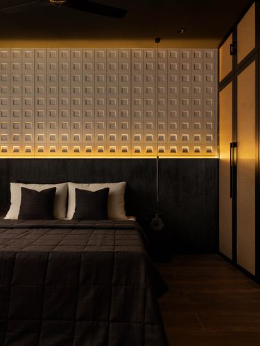 Dark hotel bedroom with textured backlit wall panel behind bed and wooden wardrobe