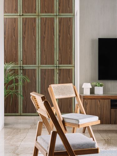 Two cane-backed folding chairs in front of a wood-paneled wardrobe with green metal trim.
