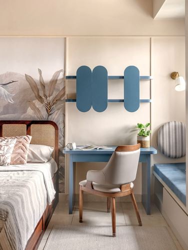Bedroom corner with cane bed, wallpaper mural, and blue desk under sculptural shelf unit