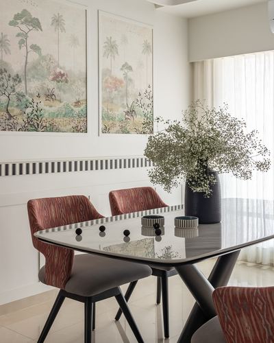 Dining table with marble top, ikat chairs, botanical wall art and a large vase of dried flowers