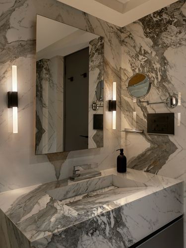 Marble bathroom vanity with sculpted marble sink, rectangular mirror, and vertical wall sconces