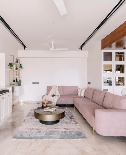 Blush pink velvet sofa and round brass coffee tables in a minimal white living room