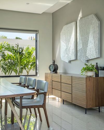 Minimalist dining area with wood table, leather chairs, wooden sideboard and textured wall panels