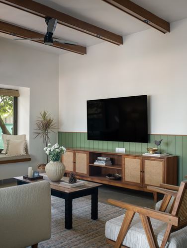 Living room with cane tv console, sage wainscoting, exposed wood beam ceiling and window seat