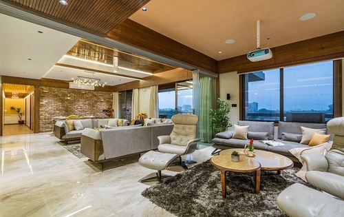 Large living room with wood ceiling, exposed brick wall, city view windows and multiple sofa groupings