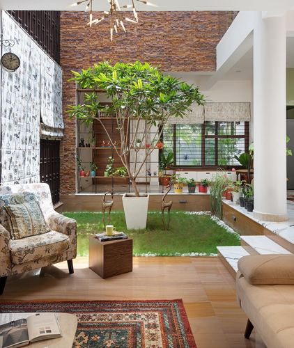 Living room opening onto internal courtyard with tree, brick wall, and layered seating