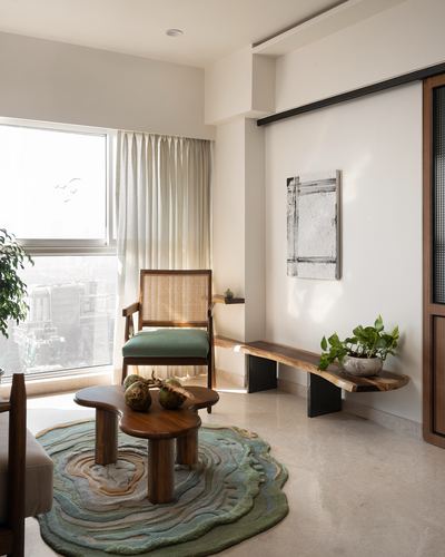 Living room corner with cane armchair, live-edge wood bench, and organic coffee table on round rug