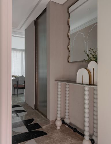 Foyer with wavy mirror, bobbin-leg console table, and black-and-white patterned floor leading to living room