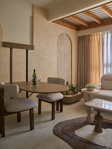Warm-toned dining nook with oval table, arched wall niche, and slatted wood ceiling detail