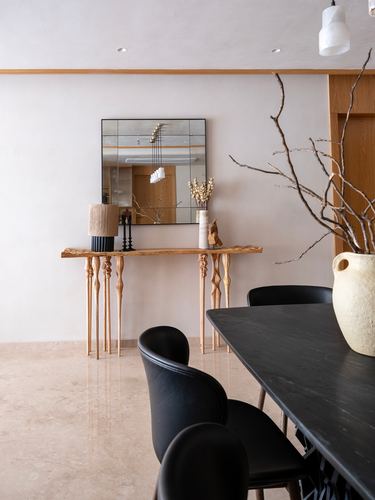 Dining area with black marble-look table, leather chairs, and a carved wood console beneath a mirror