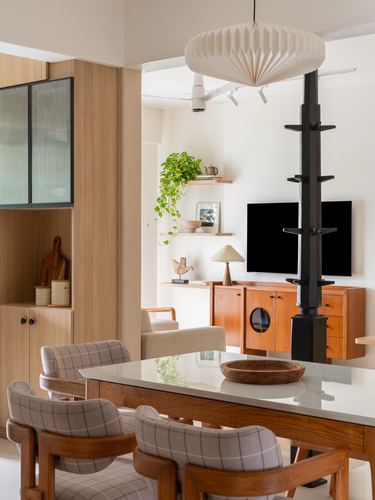 Dining table with checkered chairs opening to a living room with sideboard and wall tv