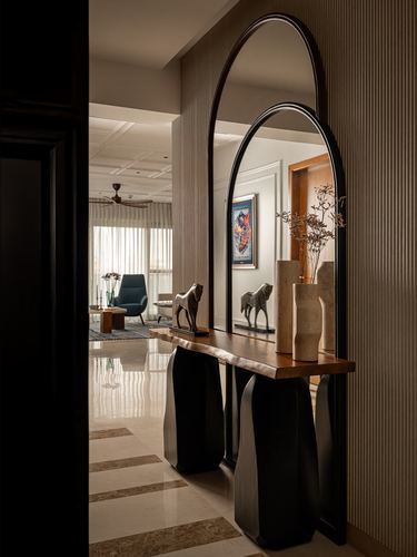 Foyer with arched black-framed mirror over wood console, horse figurines, view into living room beyond