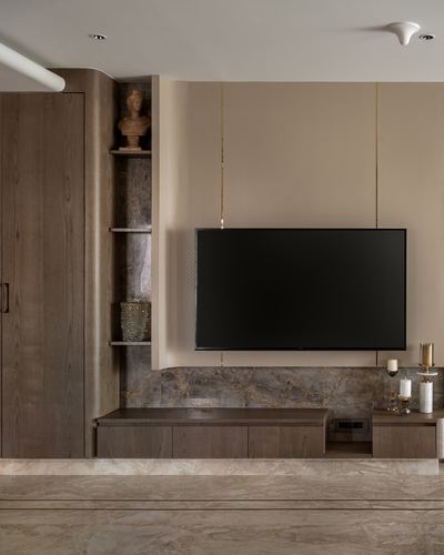 Wall-mounted TV flanked by curved wood veneer column and stone backsplash in warm living room
