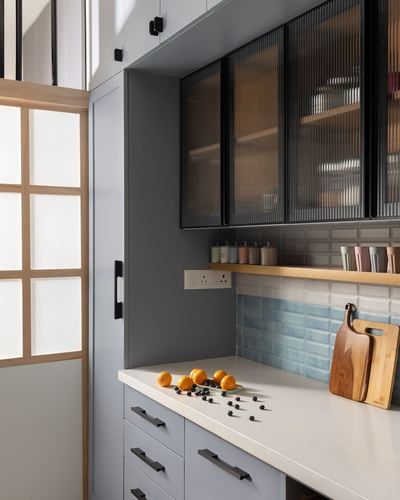 Grey kitchen corner with fluted glass cabinets, pastel blue tile backsplash, and white countertop