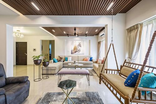 Living room with wooden slatted ceiling, hanging swing, sectional sofa and layered rugs