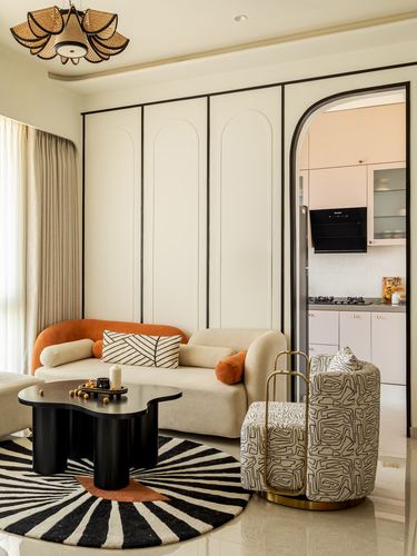 Living room with paneled wall, arched doorway to kitchen, rust-accented sofa and zebra rug