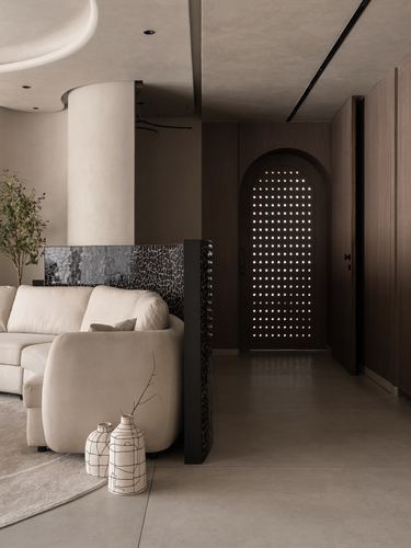 Curved beige living room with cracked-stone divider leading to a glowing perforated arched door