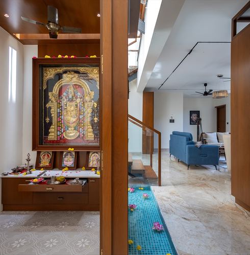 Wood-paneled pooja niche beside a teal water channel leading into an open living area
