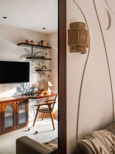View through a curved wooden door frame into a media nook with palm mural, shelves, and a rattan wall sconce beside it