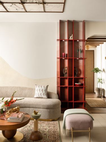Living room with curved boucle sofa, red display shelving, and layered rug