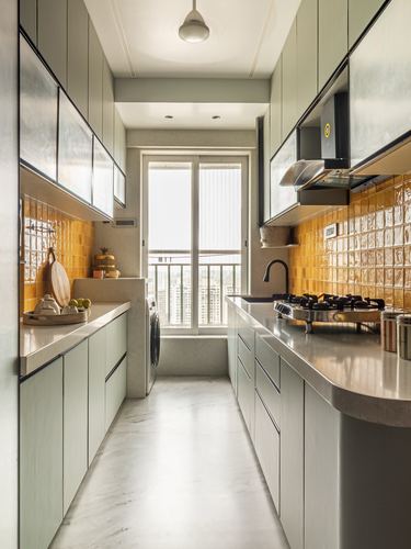 Galley kitchen with sage cabinets, mustard tile backsplash, and a bright balcony window at the end