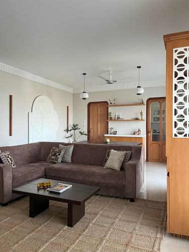 Living room with brown sectional, jute rug, carved wall relief and jaali wood cabinet