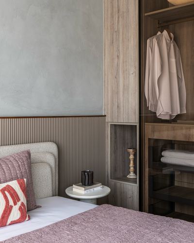 Bedroom corner with fluted wainscot, round side table, and open wardrobe with hanging shirt