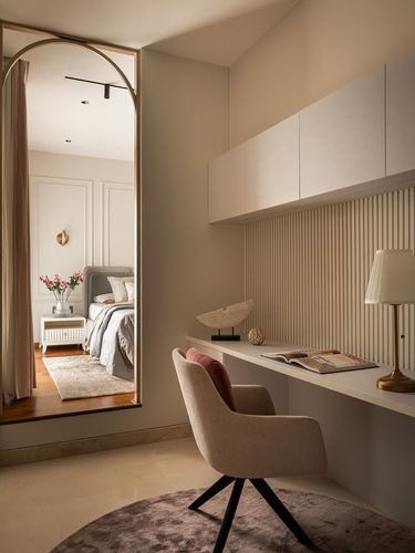 Beige study nook with fluted panel wall beside an arched mirrored doorway into a bedroom