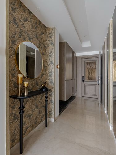 Entry foyer with round mirror over black console against patterned wallpaper, leading to marble corridor