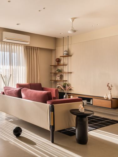 Living room with mauve velvet sofa, black round table, and fluted wall panel in raking sunlight