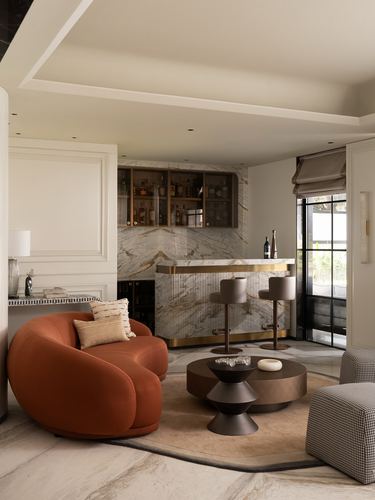 Living room with rust velvet sofa, marble-backed home bar, and round bronze coffee tables