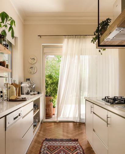 Cream galley kitchen with herringbone floor and sheer curtains at garden door, Cairo