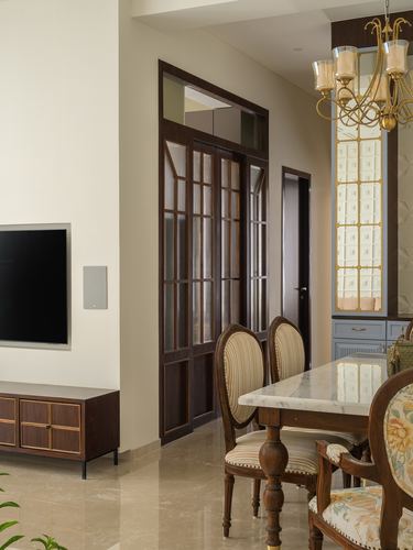 Dining area with carved wood chairs, marble-top table, and dark wood panelled glass doors beyond