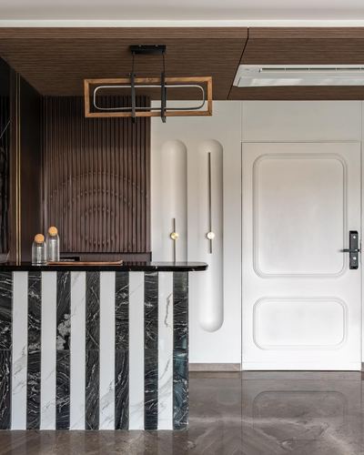 Striped black-and-white marble counter beside fluted wood wall and paneled door