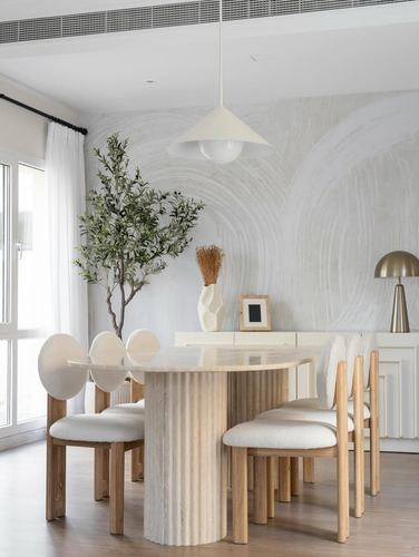 Minimalist Dubai dining room with fluted stone table, boucle chairs, and painted mural wall