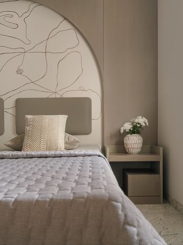 Bedroom corner with arched line-art headboard wall, upholstered headboard, and wood nightstand with vase