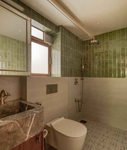 Bathroom with green glazed tile walls, marble vanity, brass fittings, and patterned floor tile