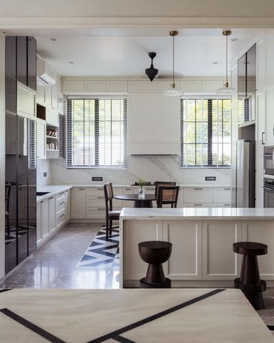 White marble kitchen with island, bar stools, and framed dining nook by windows