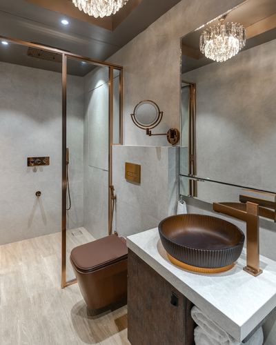 Grey stone bathroom with bronze fixtures, ribbed vessel sink, walk-in shower and crystal chandelier