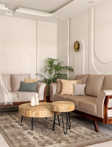 Beige living room with two sofas, wood-slice coffee tables, arched wall niches and brass sconce