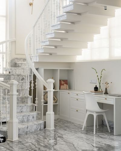White floating staircase with marble treads above a built-in study nook and desk