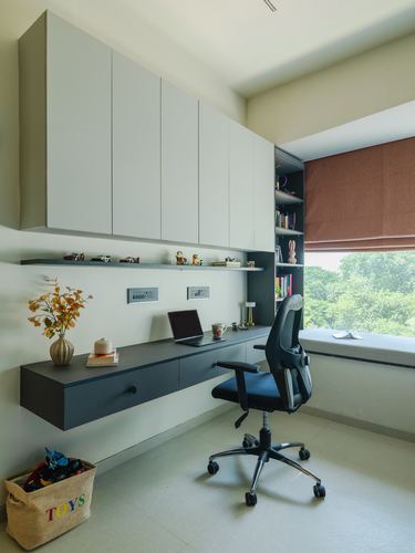 Home study nook with floating desk, wall cabinets, office chair and window seat overlooking trees