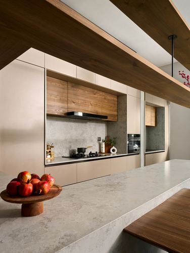Modern kitchen with beige cabinetry, stone countertop, wood accents and angled wooden ceiling beams