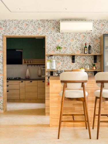 Kitchen pass-through with floral wallpaper, wooden island, and two upholstered bar stools