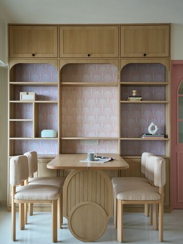 Dining nook with arched pink patterned niches built into a wooden wall unit and round table